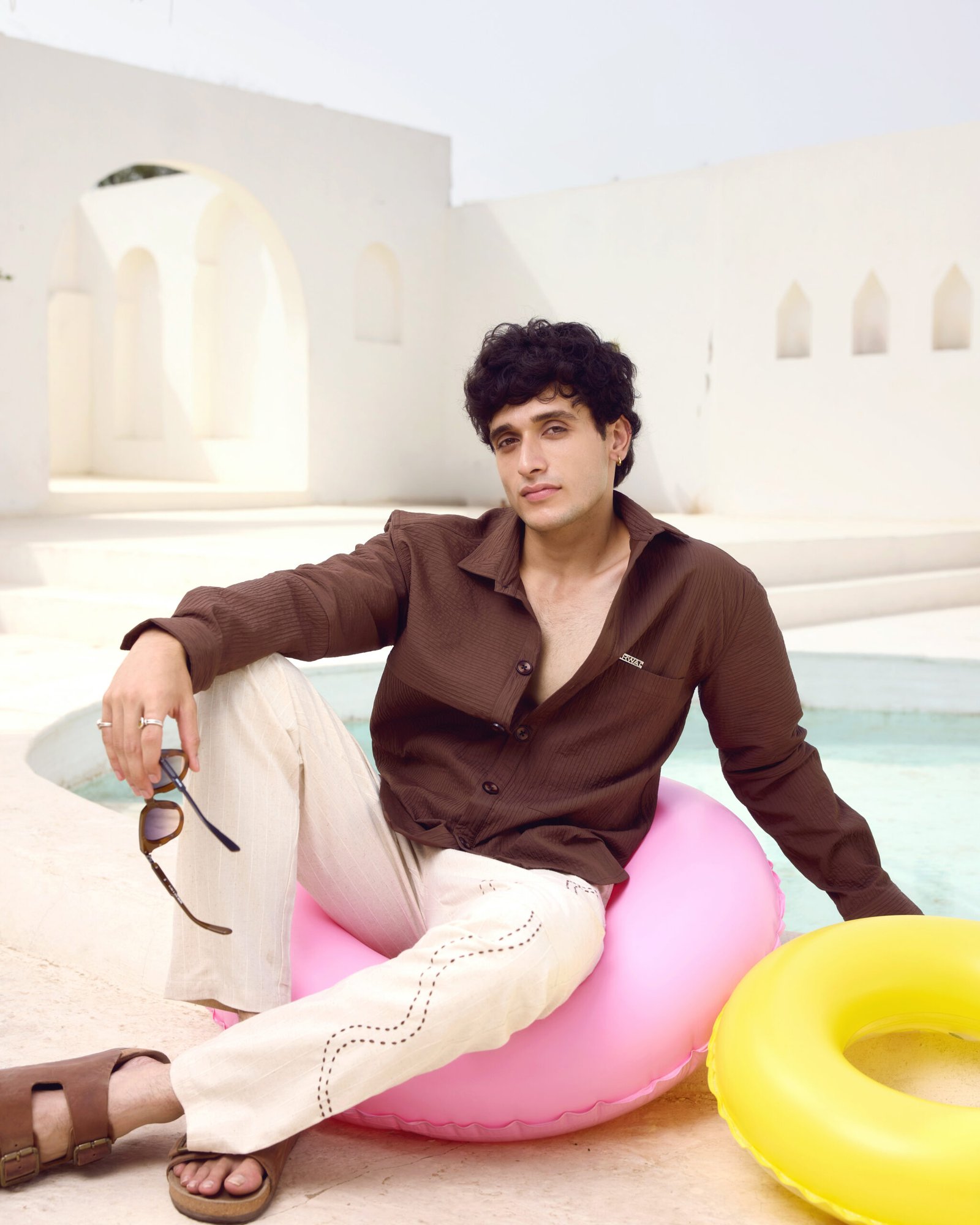 KRWA poolside shoot: model in a brown shirt on a pink float